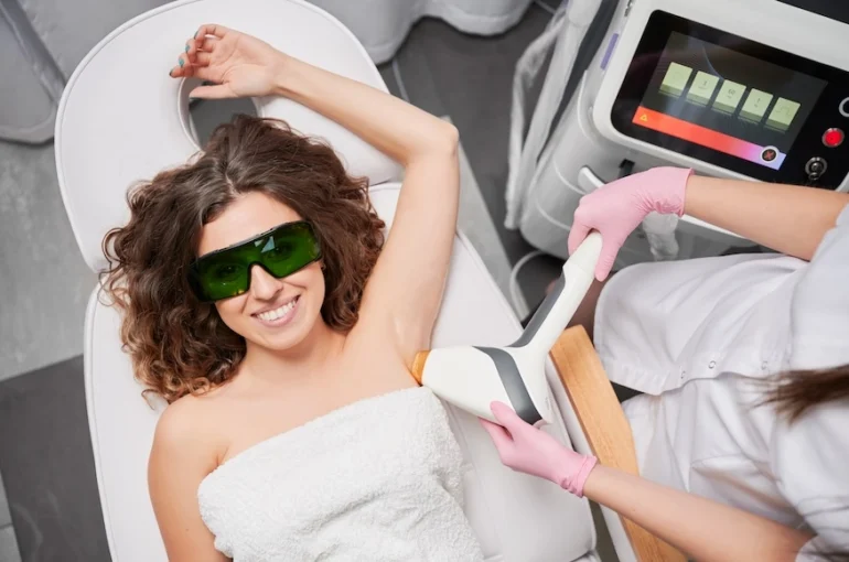 Woman laying down receiving pain free laser hair removal for her underarms.
